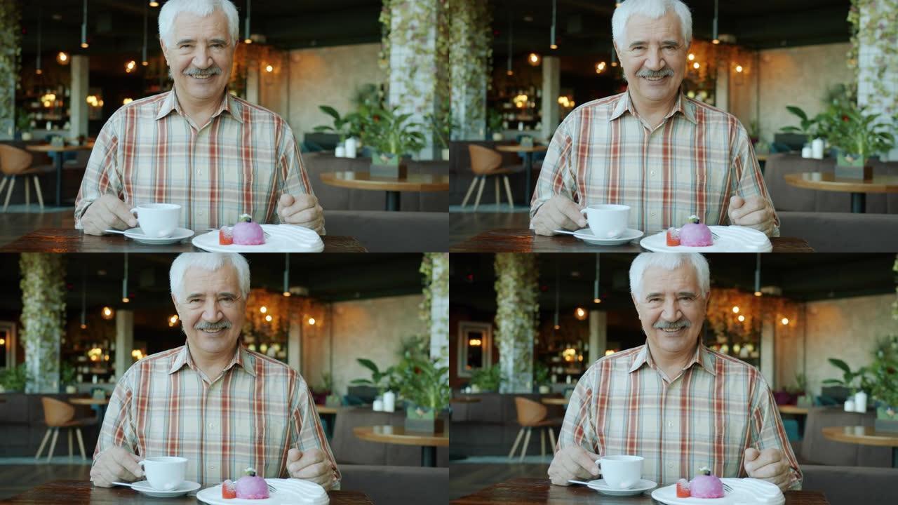 穿着便服的快乐老人的慢动作肖像在餐桌旁的咖啡馆里微笑着食物