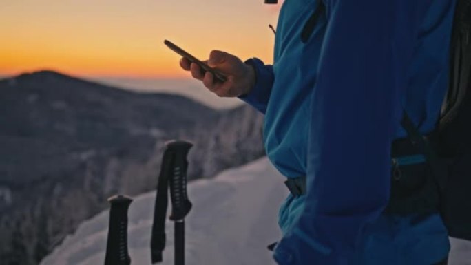 远足者女士在黄昏时在山上使用他的智能手机