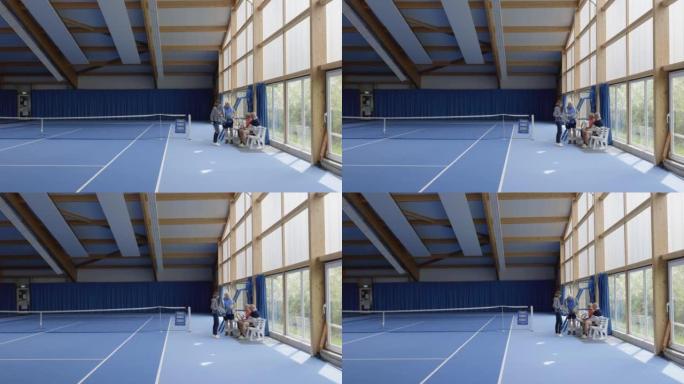 一群资深朋友在室内球场打网球后休息