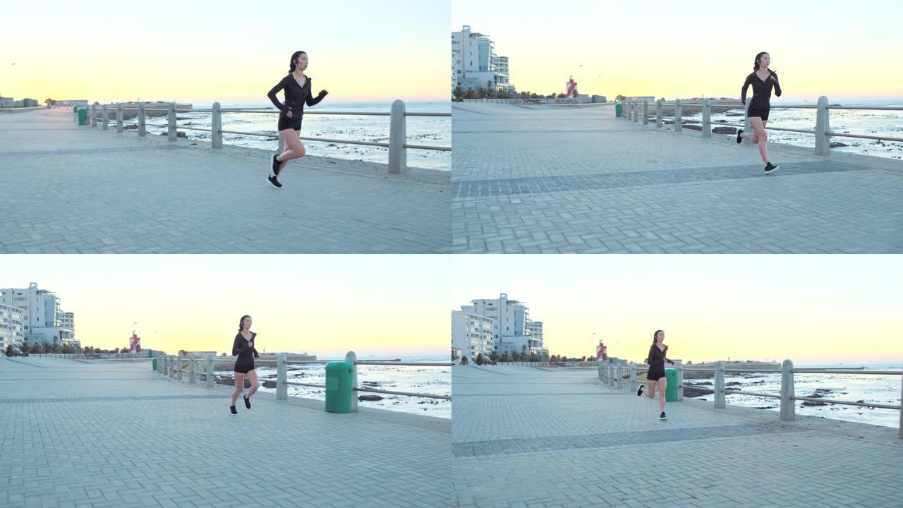 健身，女人和在南非的海滩人行道上用耳机跑步，以获取能量，马拉松和速度。女性跑步者，海洋运动和有氧运动