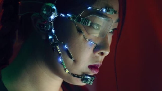 专注于赛博朋克服装和未来派眼镜的亚洲女孩在电脑上工作