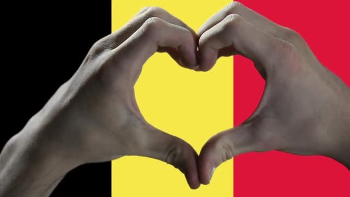 男人的手在比利时国旗上做心脏标志。特写。