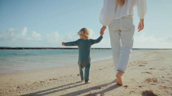 母亲和年幼的婴儿沙滩海边牵手