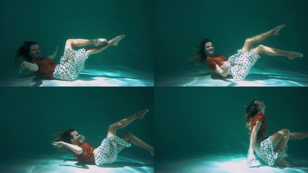 侧视图快乐有趣年轻美丽优雅的舞者女人向前躺着在水下微笑慢动作。