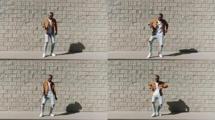 快乐的非洲裔美国舞者在砖墙上移动双腿和跳舞