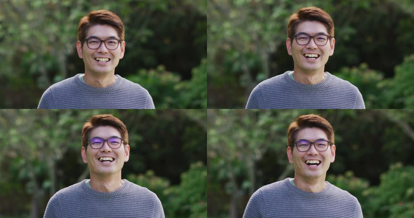 快乐的亚洲男人的肖像在花园里看着相机微笑和大笑