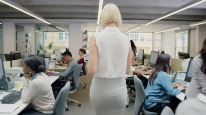 4k视频片段，一个无法识别的女商人走过繁忙的办公室并使用数字平板电脑