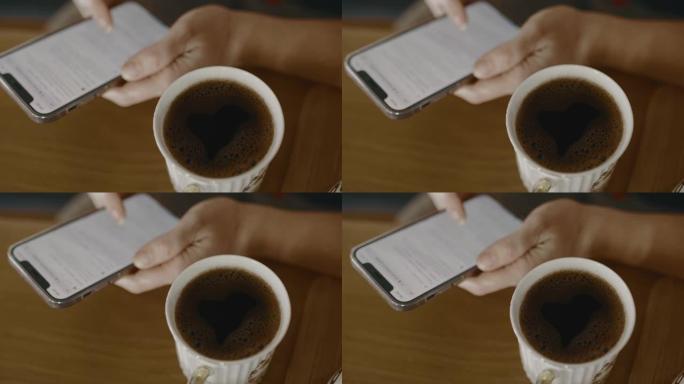 CU在一杯咖啡旁边使用智能手机，泡沫泡沫呈心形