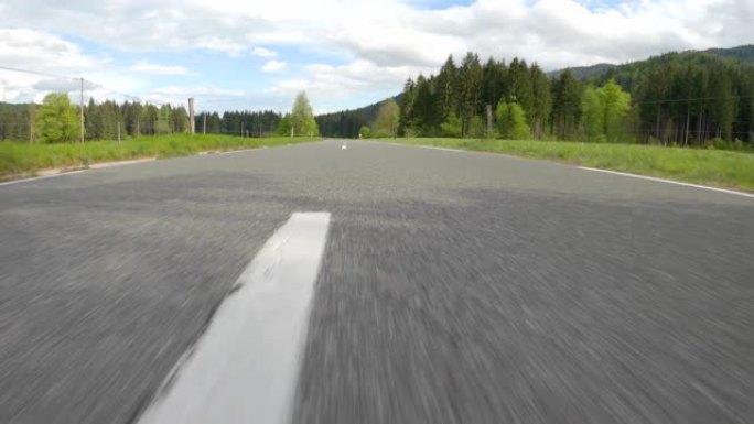 POV: 在阳光明媚的日子里，在空旷的道路上穿越美丽的绿色山谷。