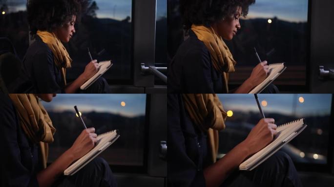 非裔美国妇女坐在公共汽车上的笔记本上用笔写字