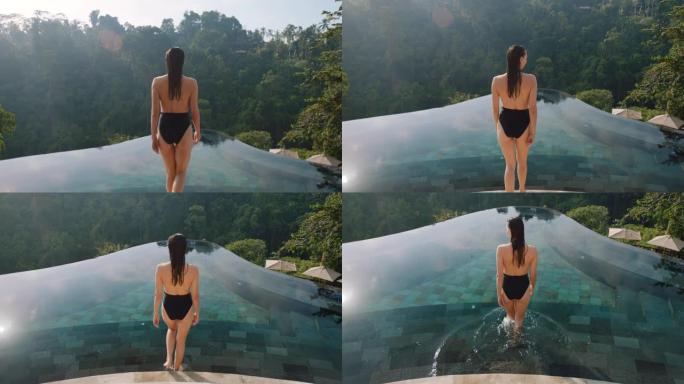 性感的女人走进无边泳池游泳，享受异国情调的暑假在酒店水疗中心享受奢华的生活方式，可以看到热带丛林4k