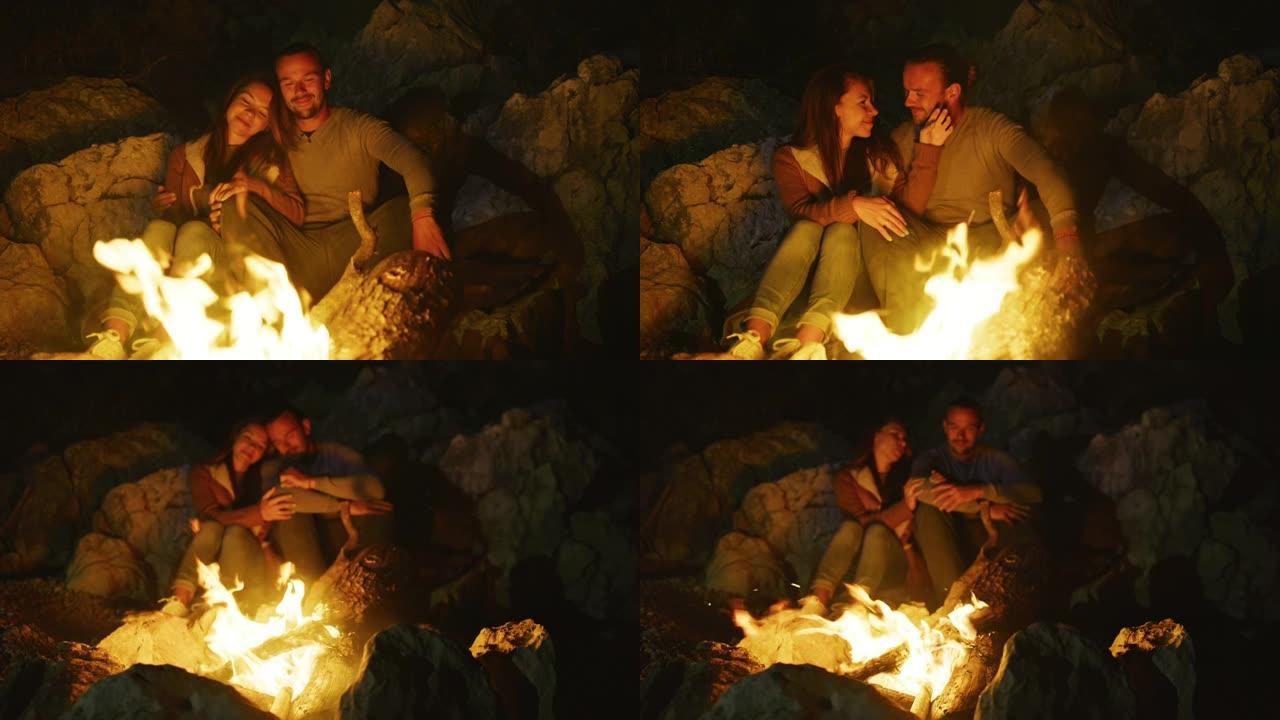 年轻夫妇坐在篝火旁拥抱