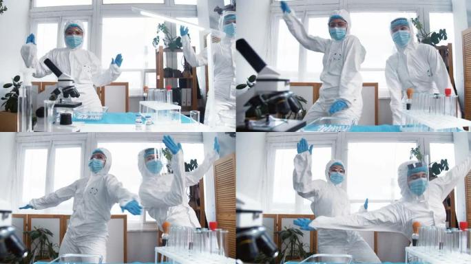 抗击病毒大流行的结束。两个穿着化学防护服的快乐有趣的女医生做疯狂的庆祝舞蹈。
