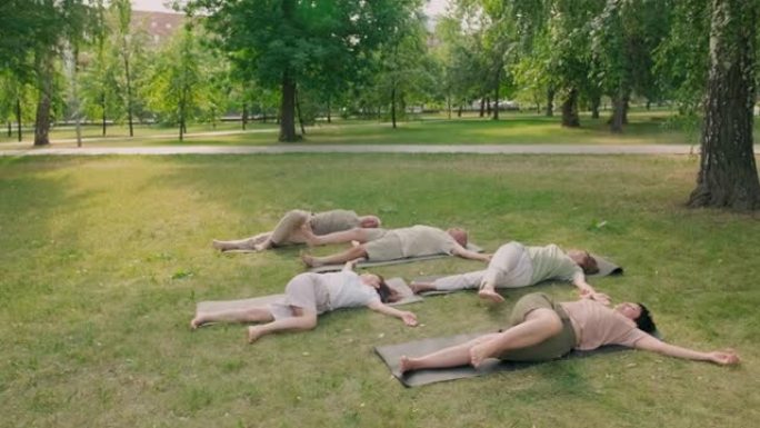 人们躺在户外瑜伽垫上伸展