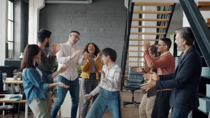 快乐的商人在办公室跳舞的慢动作享受公司聚会