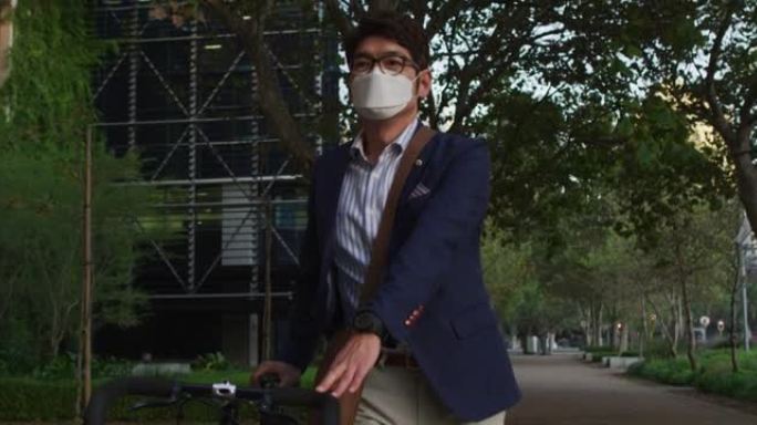 亚洲男子戴口罩与脚踏车行走街头