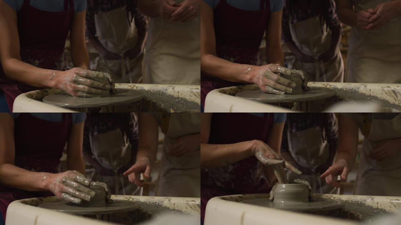 在陶艺工作室的陶艺轮上制作陶器的不同陶艺师的中间部分