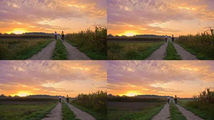 跟踪两名成年成年女性的手持照片，沿着草地土路骑行，朝着日落慢动作