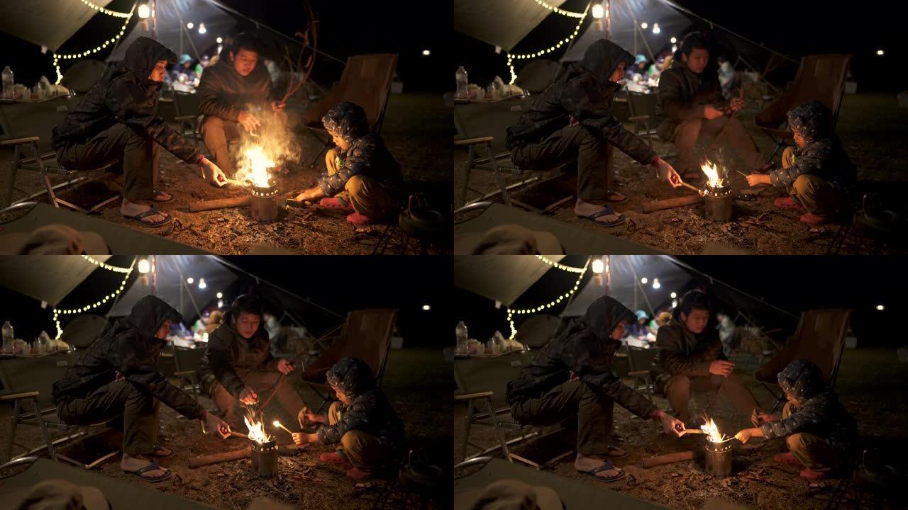 露营时坐在篝火旁的亚洲家庭