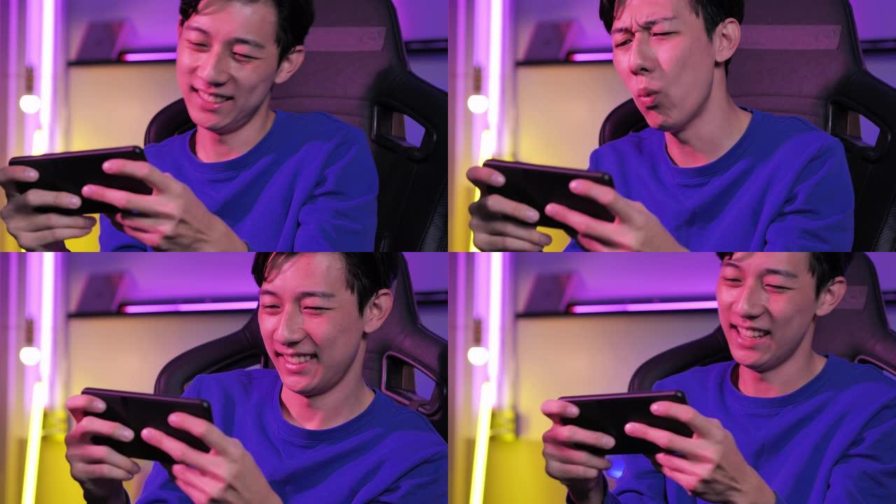激动的千禧一代和Z世代的亚洲少年男孩在智能手机上玩手机游戏eSport在线视频游戏在彩色紫外线照明客