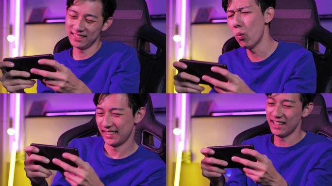 激动的千禧一代和Z世代的亚洲少年男孩在智能手机上玩手机游戏eSport在线视频游戏在彩色紫外线照明客