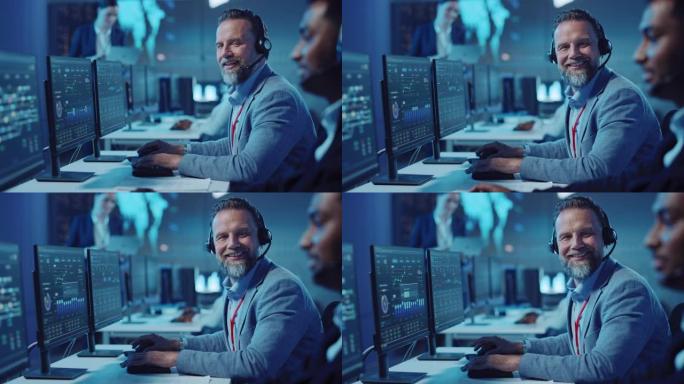 大胡子快乐的高级技术支持专家在计算机上工作时正在耳机上交谈。成功的员工转向镜头，轻轻地微笑。带显示屏
