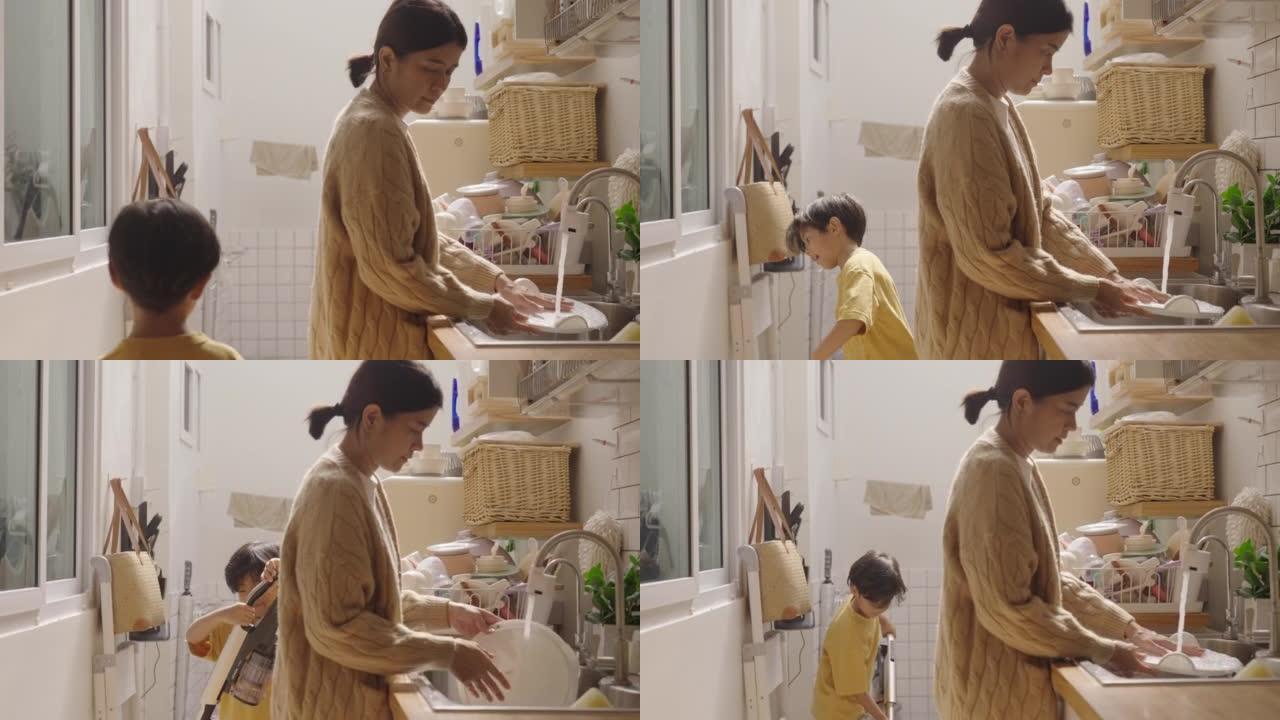 亚洲迷人的母亲教小男孩打扫厨房。