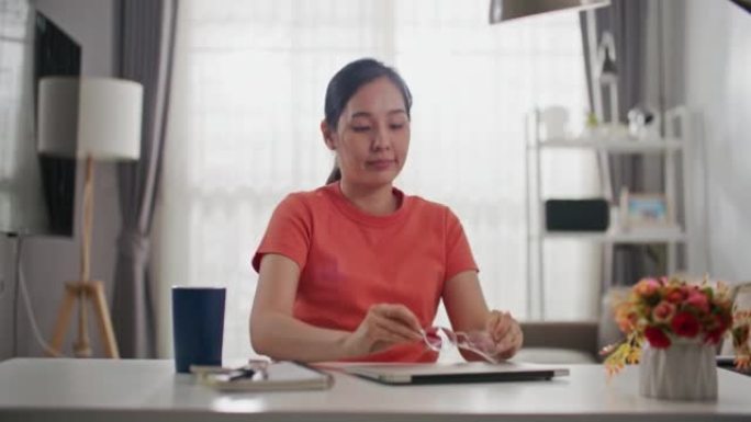 迷人的亚洲人在家里完成工作，关闭笔记本电脑放松伸展完成关闭笔记本电脑