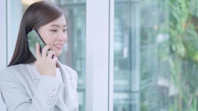 亚洲女商人在现代办公室使用智能手机行走