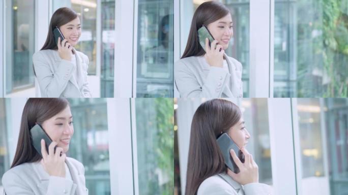 亚洲女商人在现代办公室使用智能手机行走