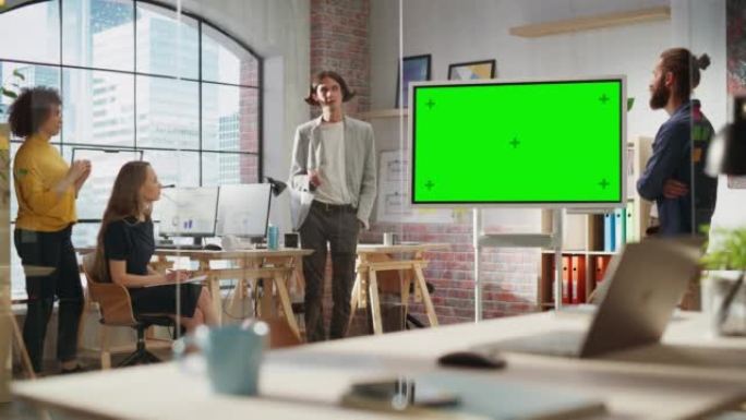 年轻商人在创意办公室会议室领导团队会议。自信时尚的经理在绿屏模拟色度键显示器上展示演示。静态镜头。