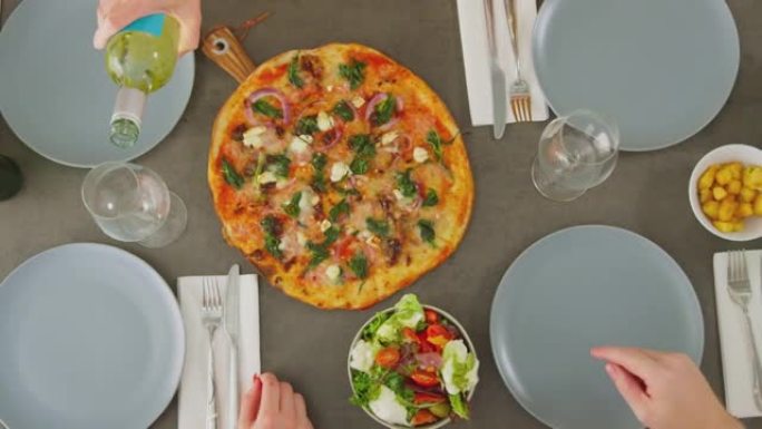 在意大利餐厅一起吃披萨，喝啤酒和葡萄酒的朋友的俯视图-慢动作拍摄