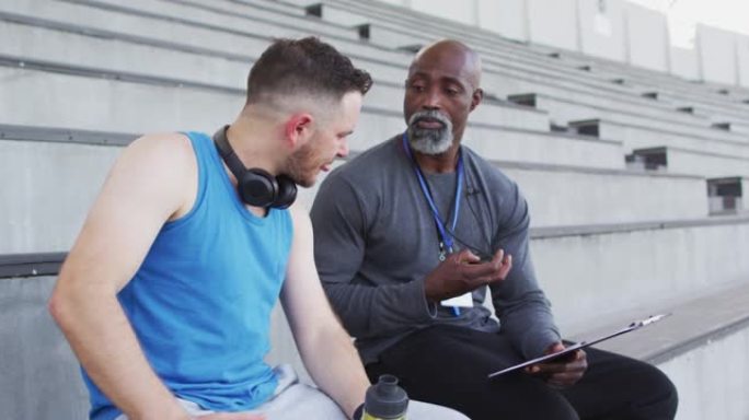多样化的男教练和运动员在夜间训练中交谈