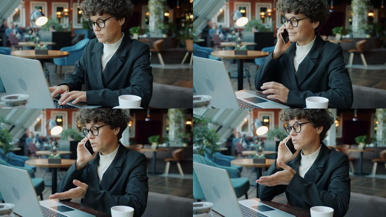 开朗的年轻商务女士在咖啡馆里用手机和笔记本电脑说话
