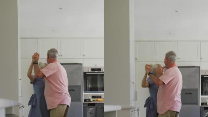 一对白人高级夫妇在厨房跳舞的垂直镜头