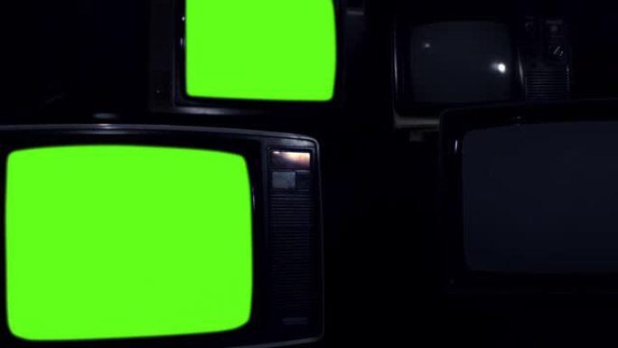 四台旧电视在黑暗的房间里打开绿色屏幕。缩小。4k分辨率。