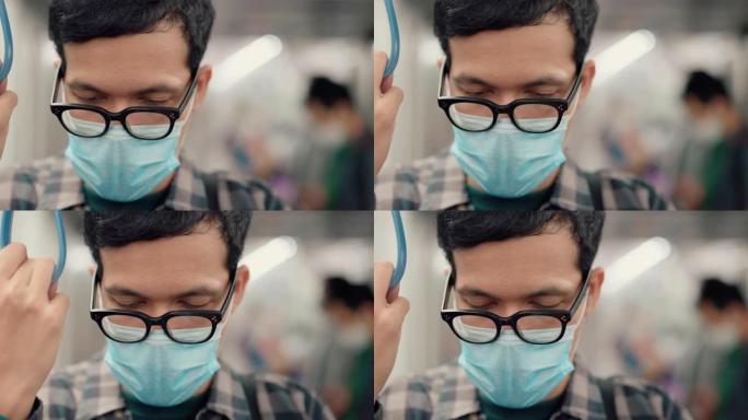 在空气污染期间乘地铁上下班的年轻亚洲男子戴上防护口罩。