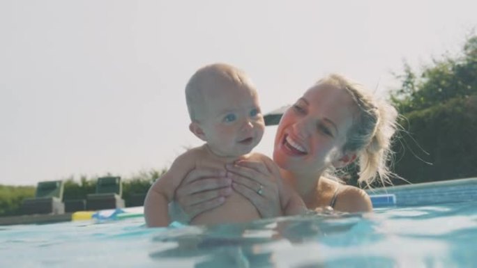 母亲带着小女儿在暑假玩得开心，在游泳池里嬉戏