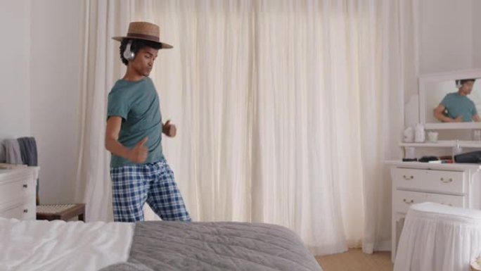 快乐的年轻人在卧室跳舞庆祝成功戴着耳机听音乐周末早上穿着睡衣跳舞
