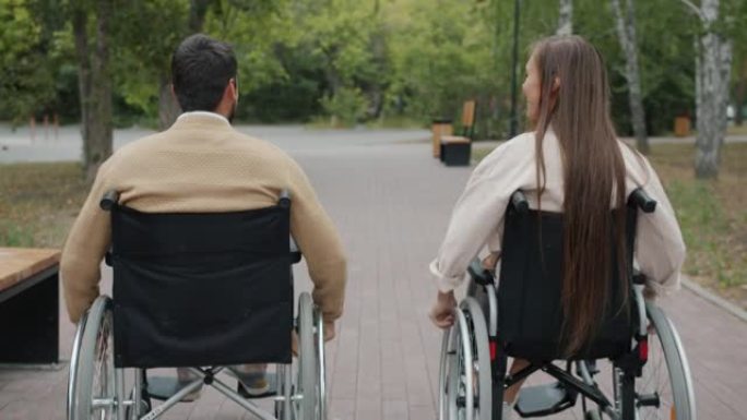 残疾人夫妇在秋季公园坐轮椅的后景微笑着享受新鲜空气