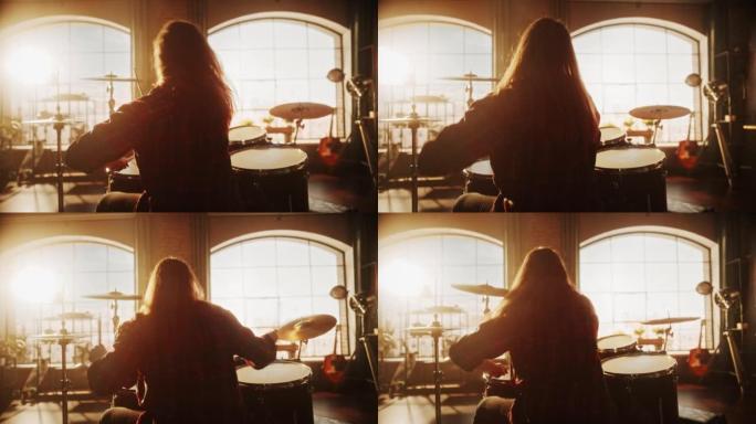 长发的女性或男性背对着镜头坐着，在阁楼工作室进行乐队排练时打鼓。重金属鼓手独自练习。暖色编辑。