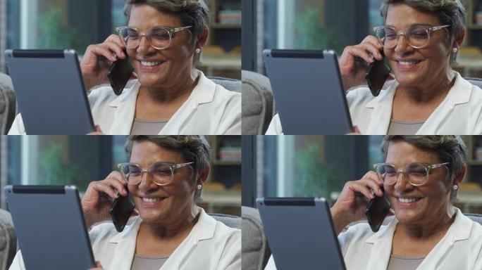 4k视频片段，一名高级妇女在家中使用数字平板电脑时在手机上聊天
