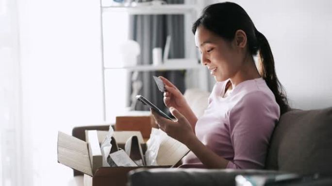亚洲女子网购在手机上输入PIN码，在家持信用卡