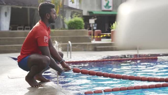 亚洲印度救生员在游泳池调节绳索准备