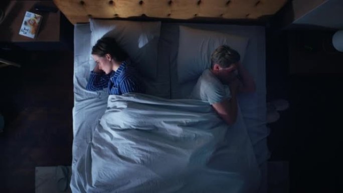 顶景公寓卧室: 晚上在床上吵架的年轻夫妇。战斗后的年轻人远离了每个人。两口之家在争论中。虐待、家庭暴