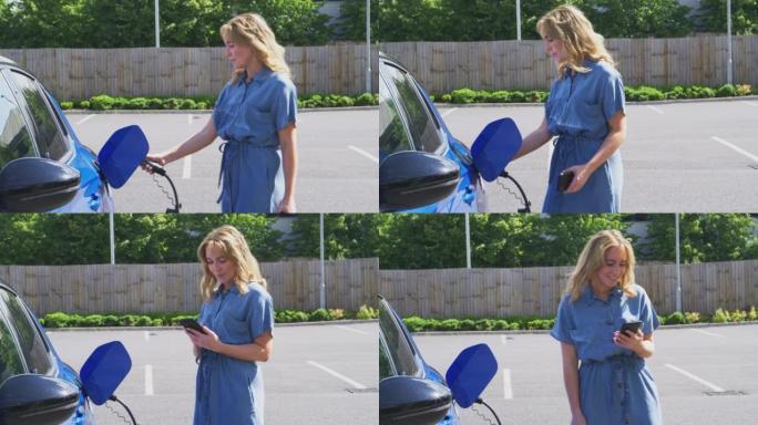 女人在户外充电站使用手机上的应用程序检查电动汽车的电池电量-慢动作拍摄