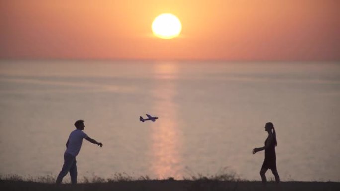 这对年轻夫妇将玩具飞机扔在海景背景上