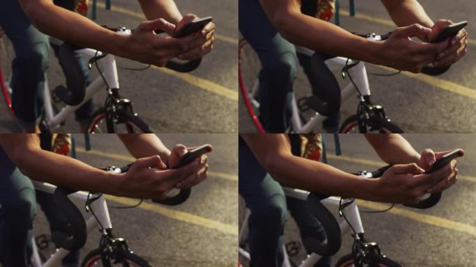 城市中的非裔美国人，使用智能手机坐在街上的自行车上