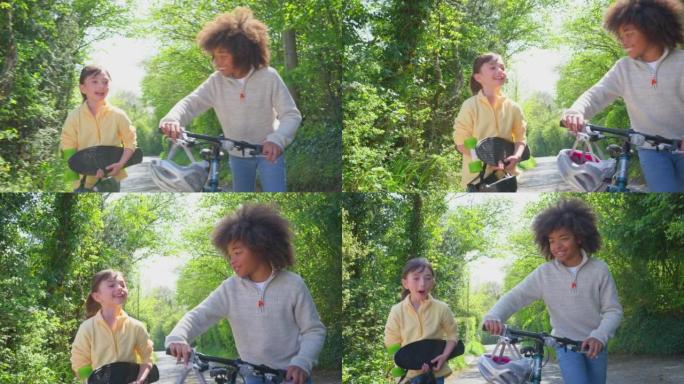 骑自行车的男孩和骑滑板的女孩沿着乡间小路一起聊天 -- 慢动作拍摄