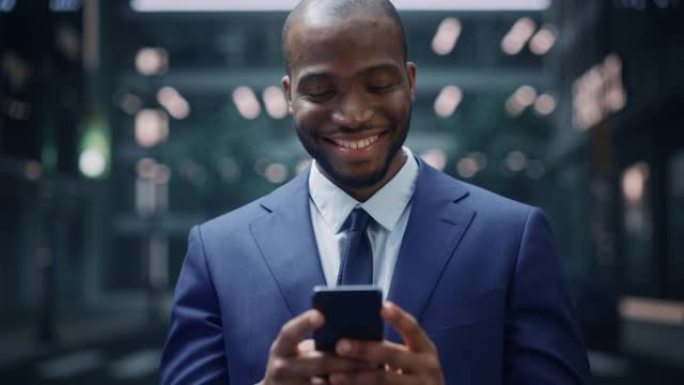 成功的非裔美国商人在城市商业区的街道上使用智能手机的肖像。黑数字创业者用手机电商App做股市投资